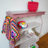 Vintage oudroze boekenkastje voor kinderkamer met sierlijke afwerking en open planken.